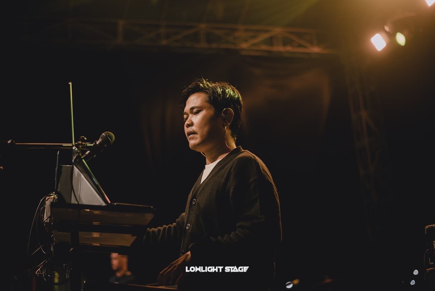 Foto horizontal Eka dengan cardigan hitam di keyboard, pencahayaan hangat. Pilihan hero utama.