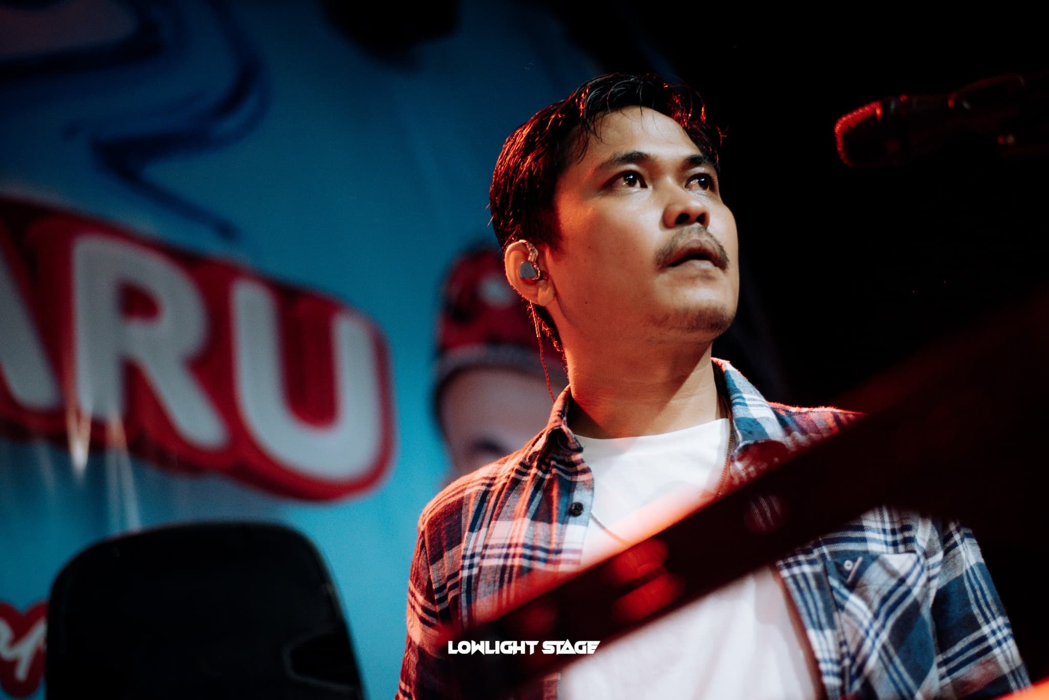 Potret dekat Eka di panggung dengan cahaya merah dan biru.