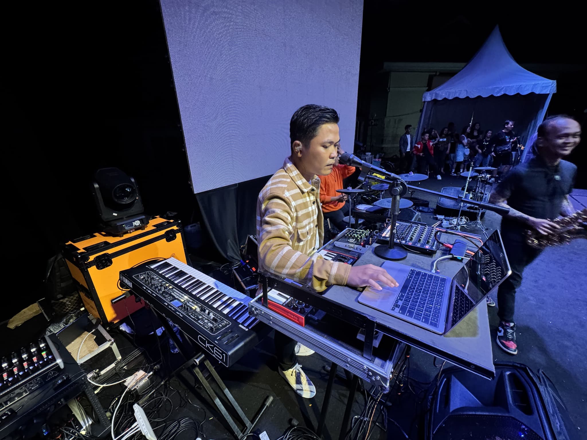 Eka mengoperasikan laptop di antara keyboard dan perangkat audio.