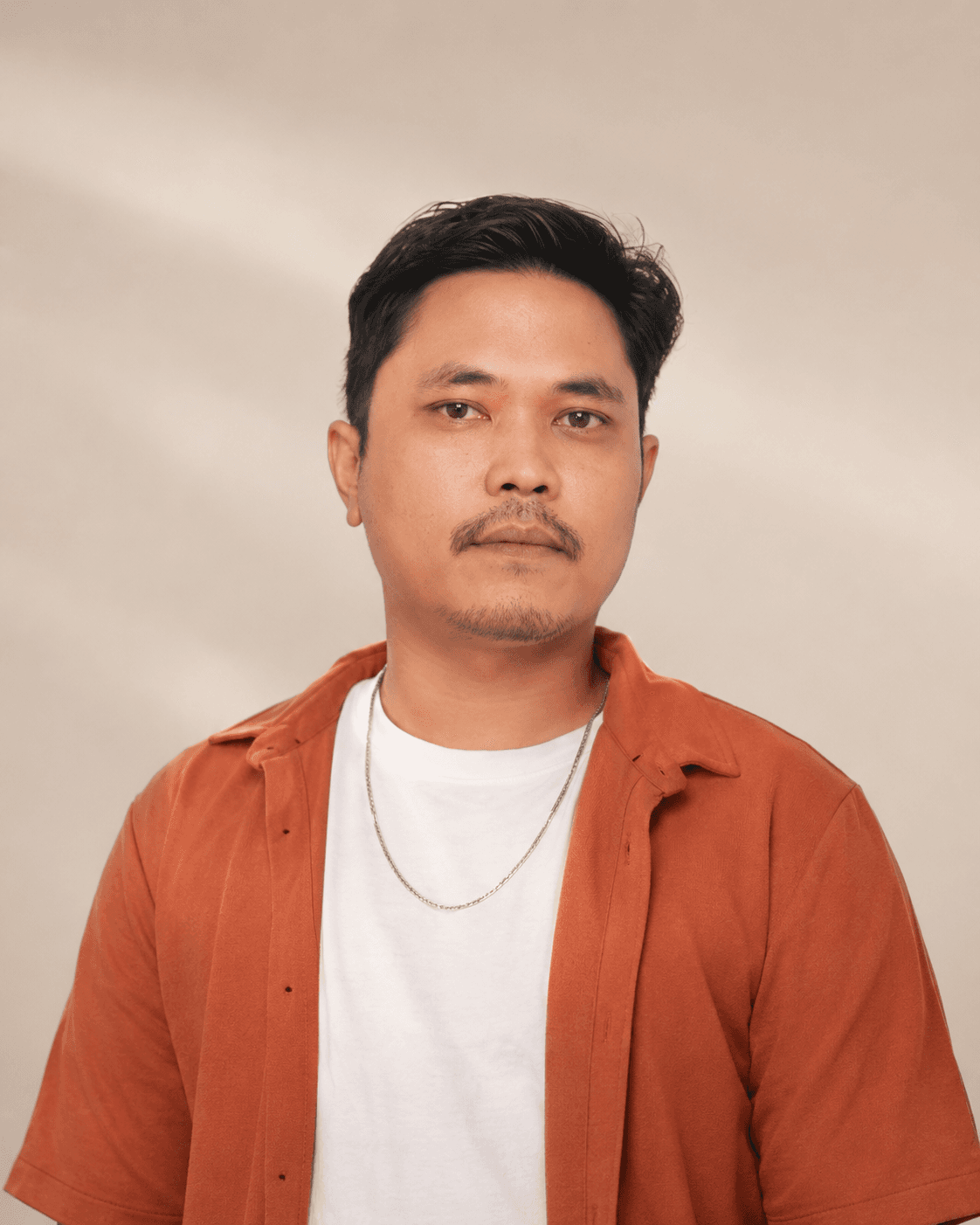Potret formal Eka berkemeja oranye. Alternatif profil dan avatar.
